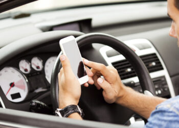Young man using smart phone in his car