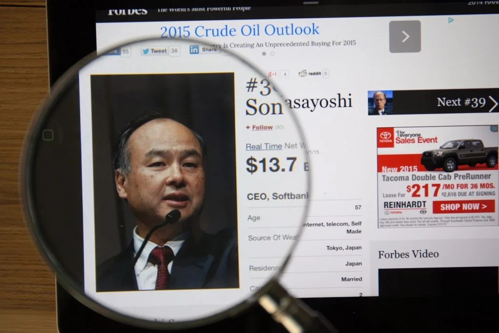 Photo of Forbes article page about Masayoshi Son on a ipad monitor screen through a magnifying glass